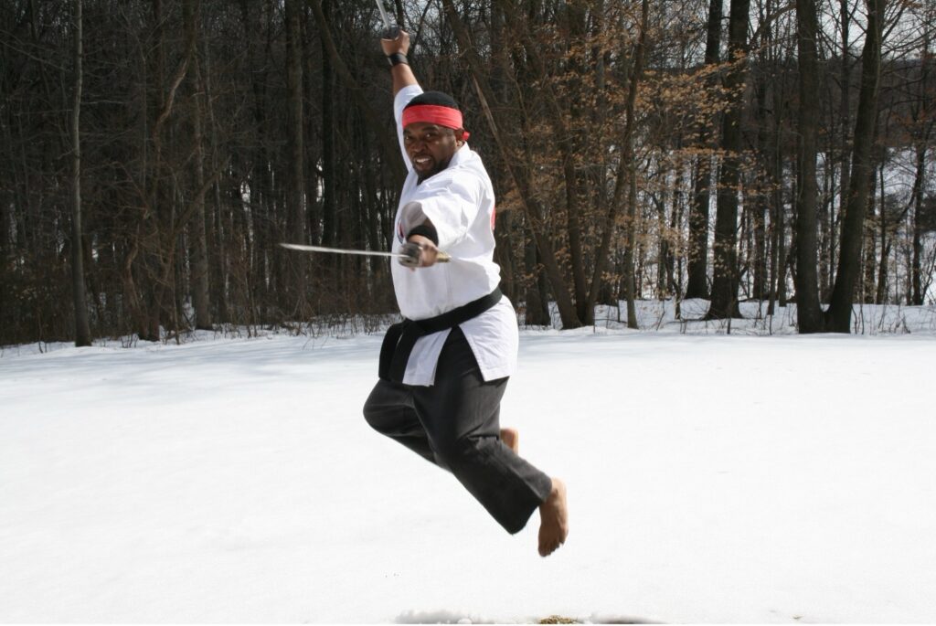 Sensei Martin Jenkins jumping with a sword in the snow.